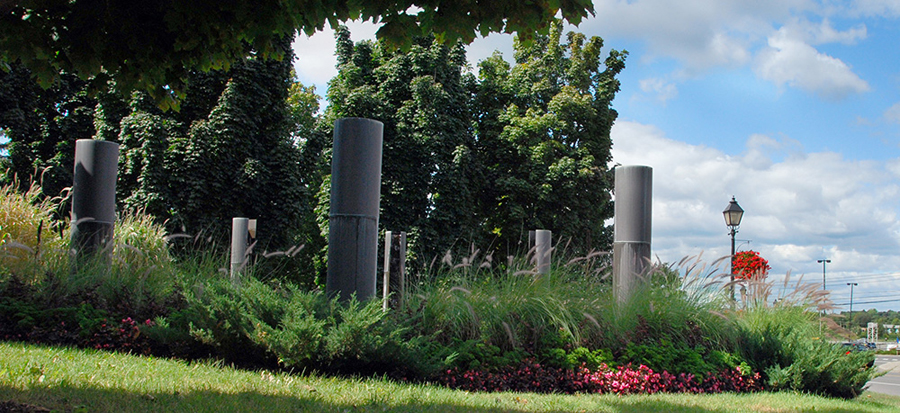 <strong>Le passage du 2 avril</strong><BR>2001<BR>Sculpture-fontaine, laiton et aménagement de la place, béton et granit<BR>6 colonnes de laiton, 358 cm de hauteur x 38 cm de diamètre<BR>Photo : Simon Meloche<BR><br><br>© Succession Charles Daudelin /SODRAC