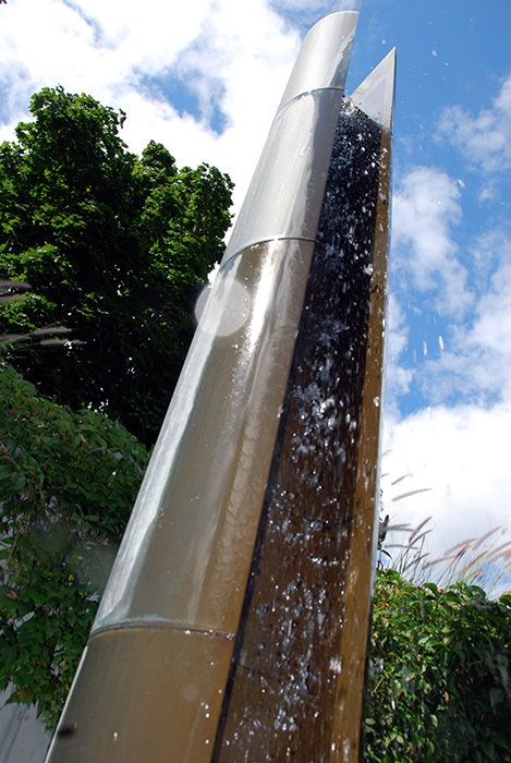 <strong><i>Le passage du 2 avril</i></strong><BR>2001<BR>Sculpture-fontaine, laiton et aménagement de la place, béton et granit<BR>6 colonnes de laiton, 358 cm de hauteur x 38 cm de diamètre<BR><i> </i><BR><BR><br><h9 style='font-size:.8em'>Photo : Simon Meloche<br>2/7</h9><BR><br><br><h9 style='font-size:.8em'>© Succession Charles Daudelin /SODRAC