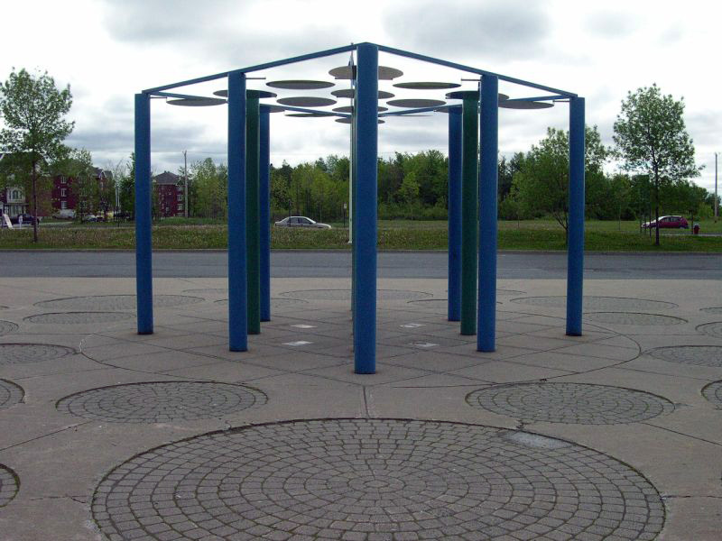 <strong><i>La Place moléculaire</i></strong><BR>1990<BR>Sculpture-cinétique et aménagement, acier peint et inoxydable<BR>13 colonnes de 3 m de hauteur, 20 cm de diam., 16 disques de 80 cm. de diam.<BR><i></i><BR><BR><h9 style='font-size:.8em'>Photo : 2/6</h9><BR><br><br><h9 style='font-size:.8em'>© Succession Charles Daudelin /COVA-DAAV